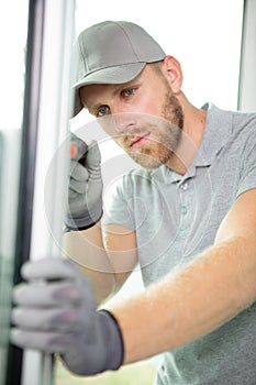 handsome young man installing bay window in construction site