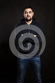 Handsome young man in jeans with a beard. Black background.