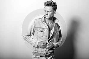 Handsome young man in jeans jacket. Black-white studio portrait.