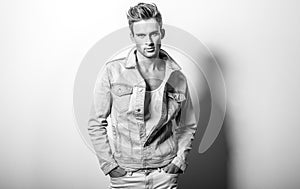 Handsome young man in jeans jacket. Black-white studio portrait.