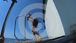 Handsome young man jumping from a boat or yacht into the sea or ocean. Summer vacation with friends. Tourists have fun