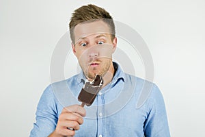 Handsome young man just bit chololate ice-cream on isolated white background