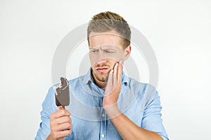 Handsome young man just bit cold chololate ice-cream and felt toothache on isolated white background