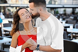 Handsome young man kissing his beautiful girlfriend on city street