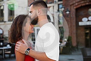 Handsome young man kissing his beautiful girlfriend on city street