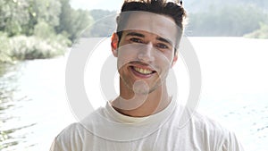 Handsome young man on a lake`s shore or river