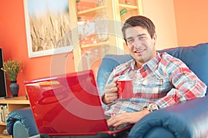 Handsome young man with laptop and coffee cup