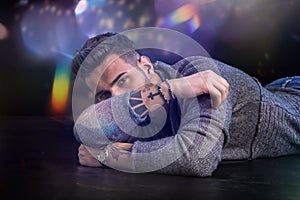 Handsome young man laying on black background l