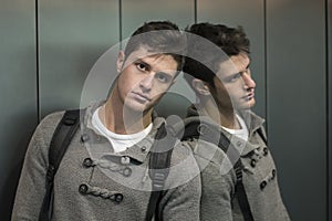 Handsome young man leaning against mirror in elevator (lift)