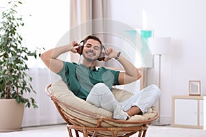 Handsome young man listening music in armchair