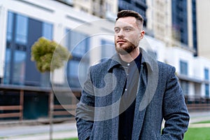 Handsome young man looking into urban street. Succesful businessman walking down the street