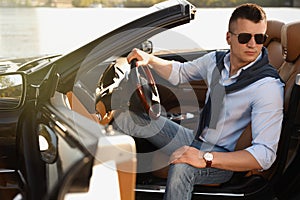 Handsome young man in luxury convertible car