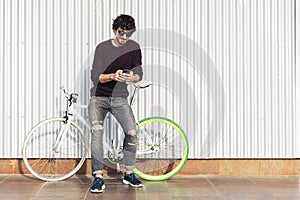 Handsome young man with mobile phone and fixed gear bicycle.