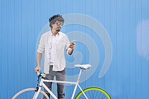 Handsome young man with mobile phone and fixed gear bicycle.