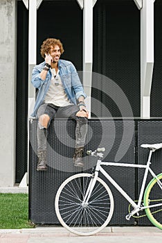 Handsome young man with mobile phone and fixed gear bicycle.