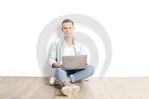 Handsome young man model sitting, posing on white wall background, wide smile. Hipster casual street style, plain unbuttoned baby