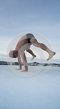 Handsome young man with naked torso doing brake dancing movements on a rooftop