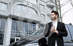 Handsome young man near modern car, low angle view