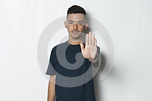 Handsome young man with open hand doing stop sign with serious expression defense gesture isolated on white background