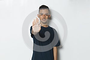 Handsome young man with open hand doing stop sign with serious expression defense gesture isolated on white background