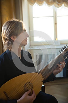 Handsome young man playing antique lute