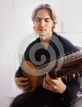 Handsome young man playing antique lute