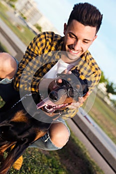 Handsome young man playing with his dog in the park.