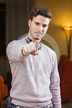 Handsome young man pointing finger at you, smiling