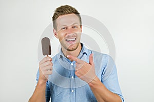 Handsome young man points at tasty chololate ice-cream with his finger on isolated white background