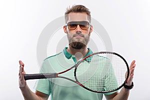Handsome young man in polo shirt holding tennis