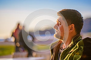Handsome young man in profile close-up. A tourist enjoys a bright sunset on the coast of the winter sea