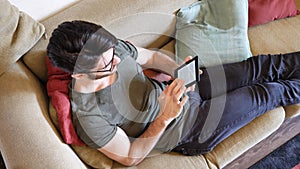 Handsome young man reading ebook on sofa