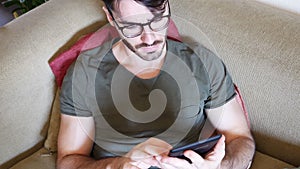 Handsome young man reading ebook on sofa