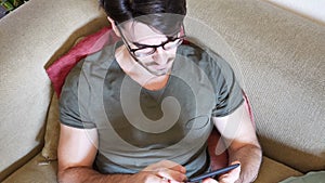 Handsome young man reading ebook on sofa