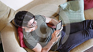 Handsome young man reading ebook on sofa