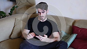 Handsome young man reading ebook on sofa