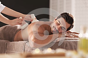 Handsome young man receiving herbal bag massage