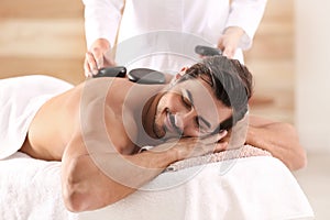 Handsome young man receiving hot stone massage