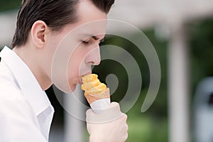 Handsome young man refresh himself eating a delicious mango sorbet