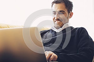 Handsome young man relaxing at home with a laptop computer balanced
