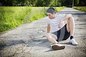 Handsome young man resting sitting on road after