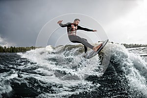 Handsome young man rides a wave with his surfboard. .