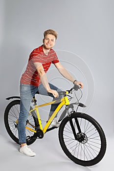 Handsome young man riding bicycle on background