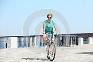 Handsome young man riding bicycle outdoors