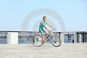 Handsome young man riding bicycle outdoors