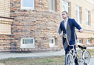 A handsome young man rolling his bicycle