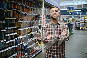 handsome young man shopping for tools at hardware store