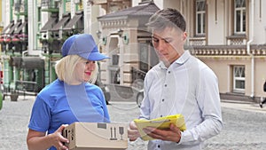 Handsome young man signing papers receiving a package from delivery woman
