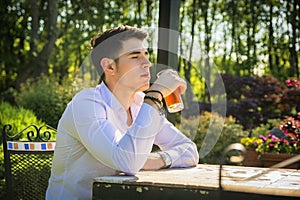 Handsome young man sitting alone at table outside