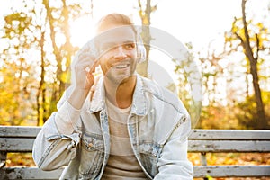 Handsome young man sitting on a bench in the autumn park